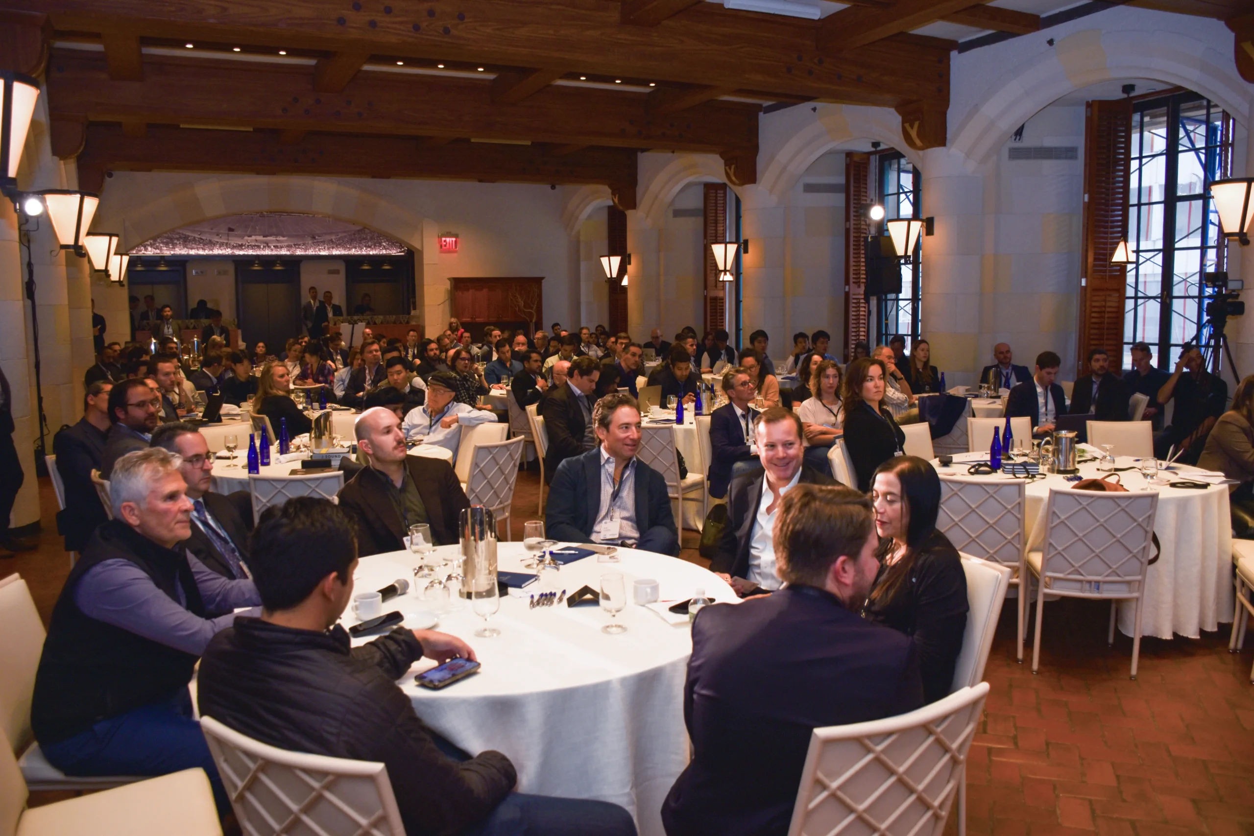 A group of business people sitting around tables at the AlphaMarket business conference